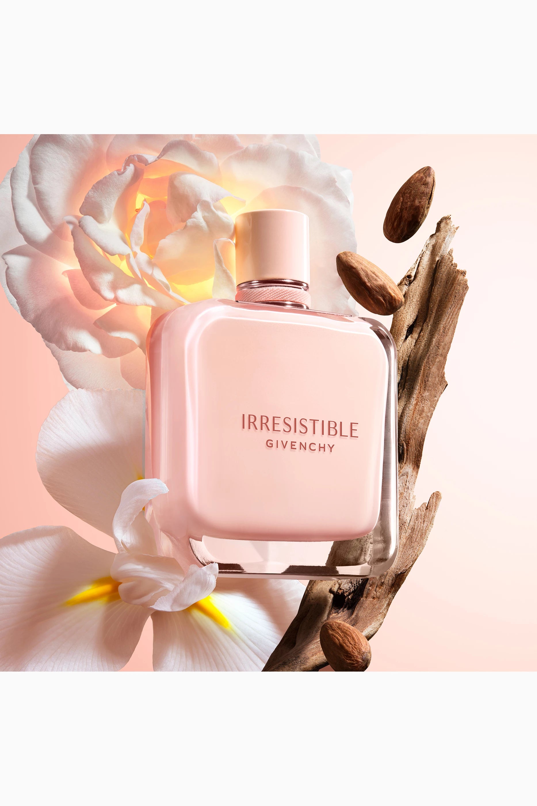Givenchy Irresistible perfume bottle with flowers and wood elements on a soft pink background