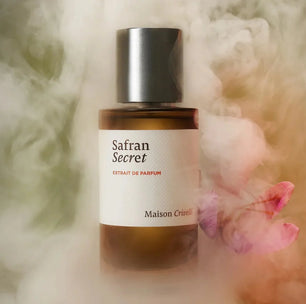 Perfume bottle labeled 'Safran Secret' by Maison Crivelli with a soft, blurred background.