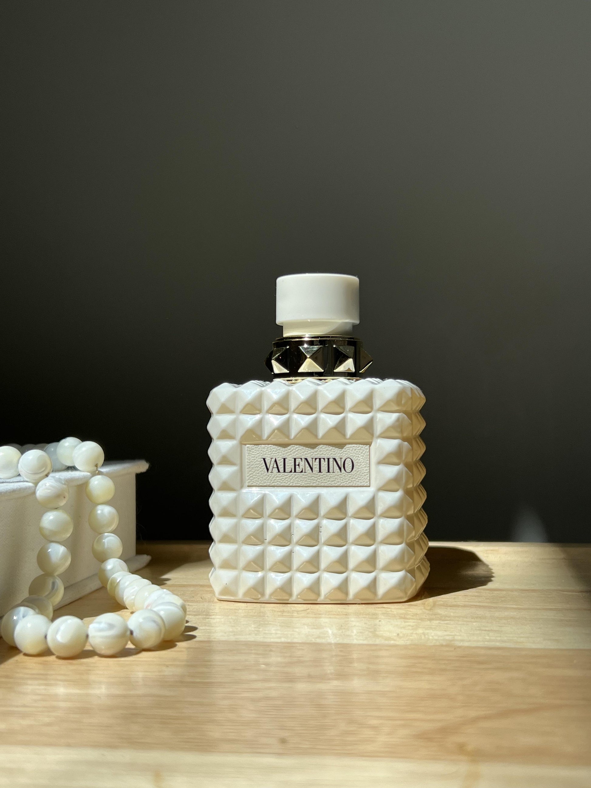Valentino perfume bottle with textured design on a wooden surface