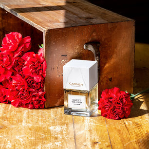 Carnier Sweet William perfume bottle with red flowers on a wooden surface