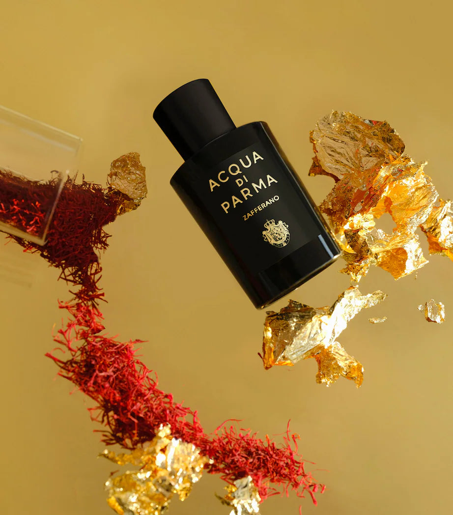 Acqua di Parma perfume bottle with saffron and gold elements on a yellow background