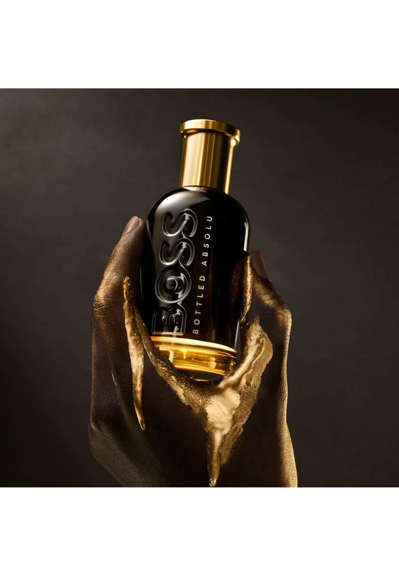 Bottle of Hugo Boss perfume held by a hand against a dark background