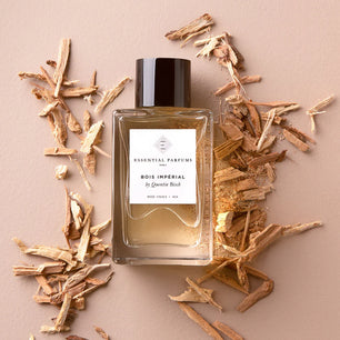Perfume bottle labeled 'Bois Imperial' by Essential Parfums on a beige background with wood chips.