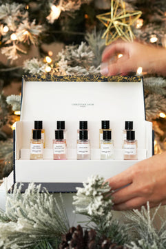 Set of perfume bottles in a gift box with a Christmas tree in the background
