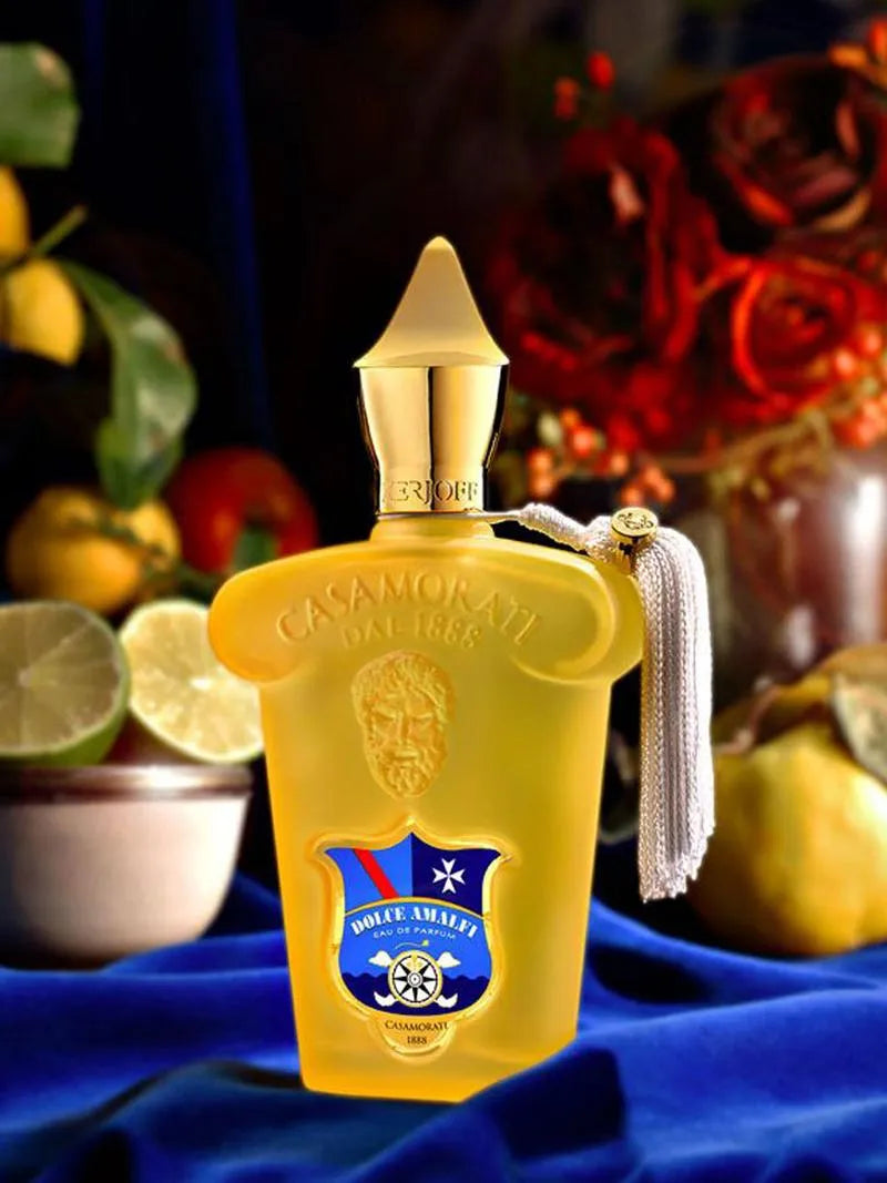 Yellow perfume bottle with gold cap on a blue fabric background