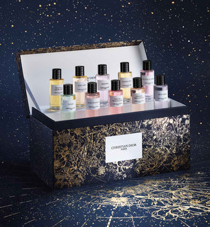 Collection of Christian Dior perfume bottles in a decorative box against a starry night sky background.