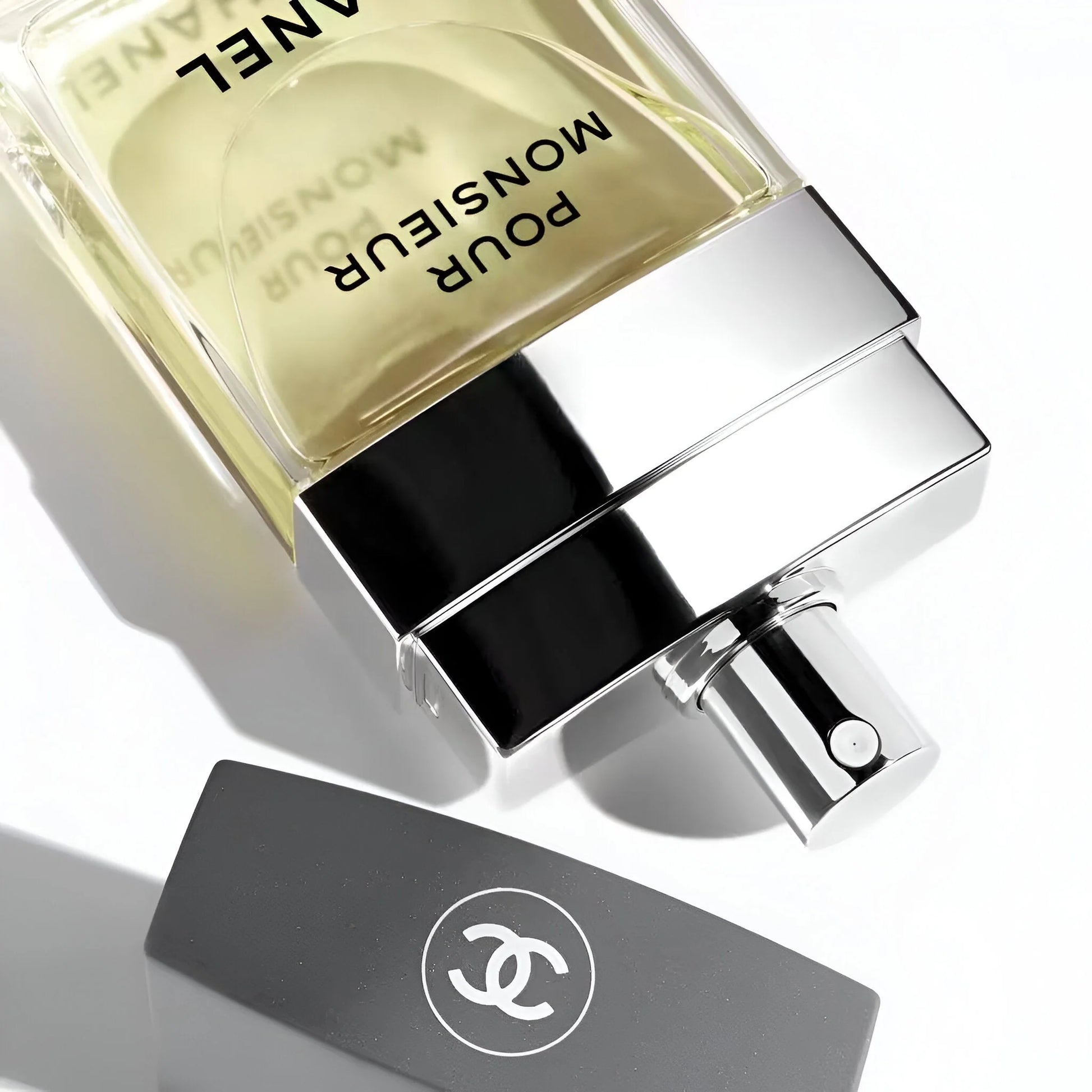 Chanel Monsieur Pour Homme perfume bottle on a reflective surface with a white background