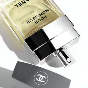 Chanel Monsieur Pour Homme perfume bottle on a reflective surface with a white background