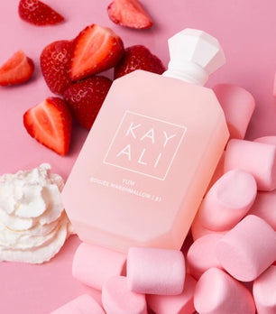 Pink bottle labeled 'KAY ALI' surrounded by strawberries and pink marshmallows on a pink background