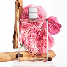 Glass perfume bottle with pink flower design on a wooden surface